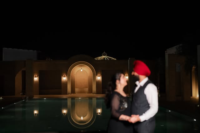 A couple sharing a romantic moment beside an illuminated pool